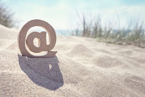 Email @ symbol in the sand at the beach